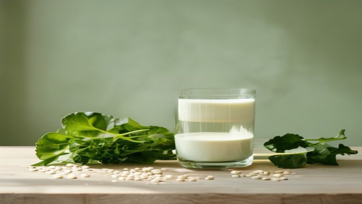 Ly sữa, đậu phụ và rau lá xanh đậm trên bàn gỗ sáng