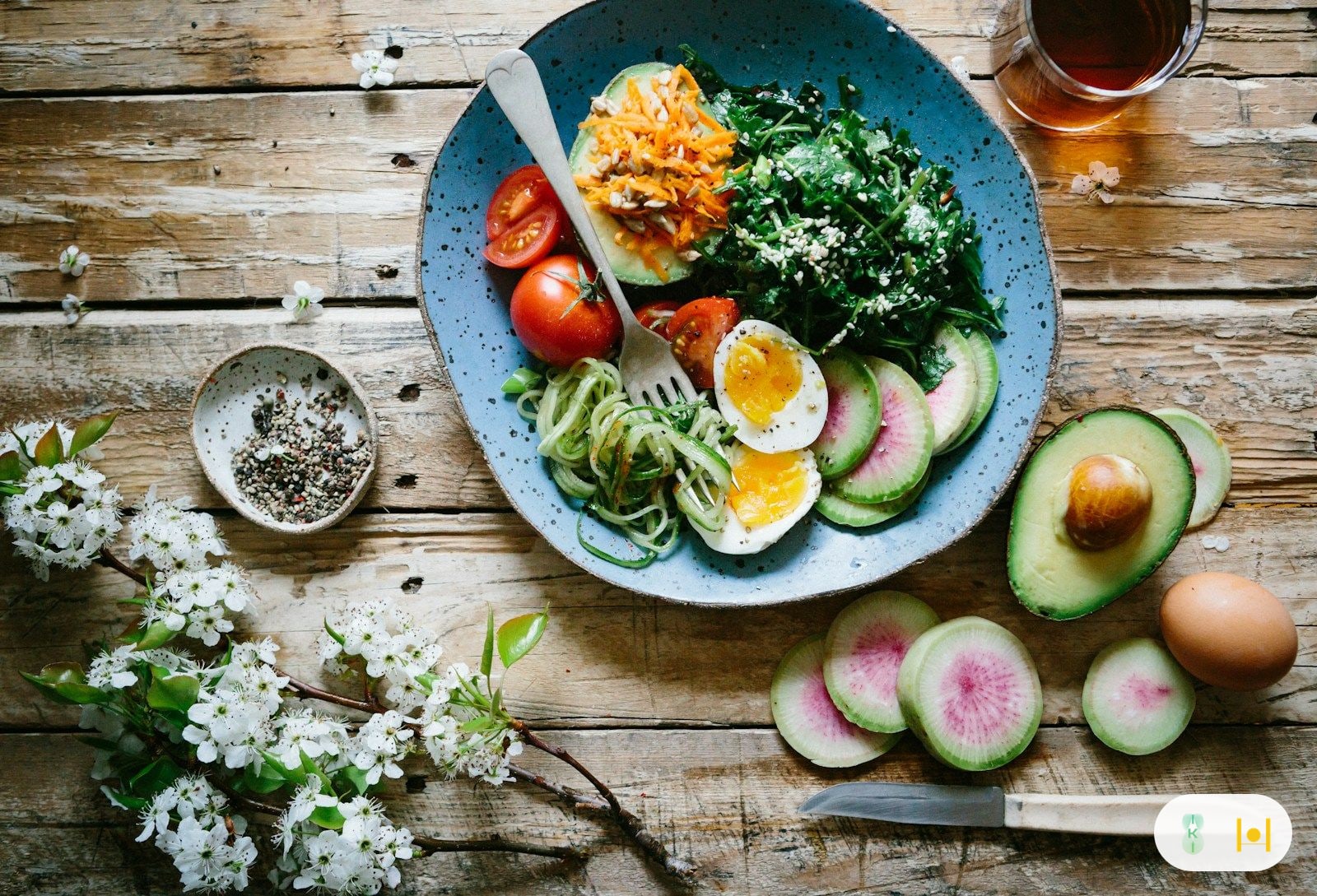 Một người trẻ ngồi bên bàn làm việc với ly nước và bữa ăn nhẹ lành mạnh, ánh sáng buổi sáng dịu