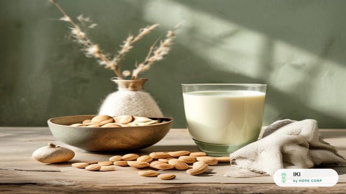 Ly sữa hạt bên cạnh bát hạnh nhân và hạt điều trên bàn gỗ